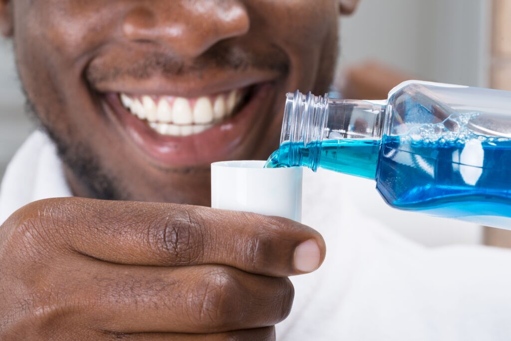 Man measuring mouthwash and smiling.